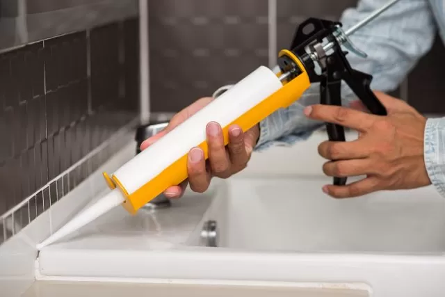 Man using sealant to prevent water leakage in bathroom